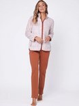 Vrouw in een roze teddy fleece jack met oranje bies en bruine joggingbroek.