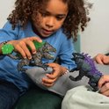Een jongen met krullend haar speelt met twee Eldrador Creatures speelfiguren: een grijze, ruwe 'Rotsbreker' met groene kristallen, en een zwarte 'Schaduw Lynx' met paarse stekels.
