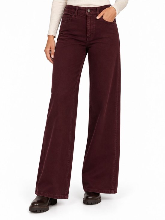 Bordeauxrode wijde jeans met hoge taille en knoopsluiting, gedragen met een beige top en donkere boots.