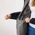 Femme portant un haut blanc et un jean, montrant l'intérieur d'une veste noire avec un cordon de serrage.