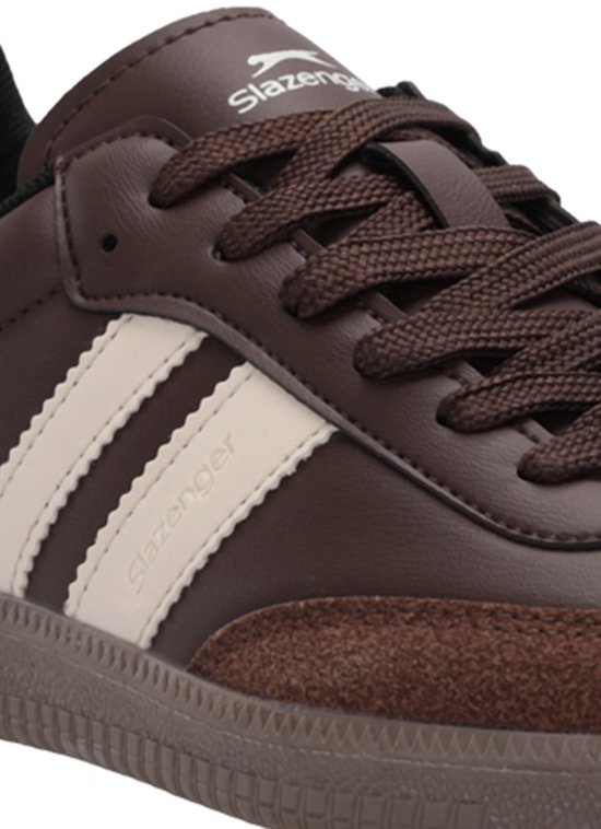 Close-up van bruine Slazenger sneaker met beige strepen en suède accenten bij de neus.