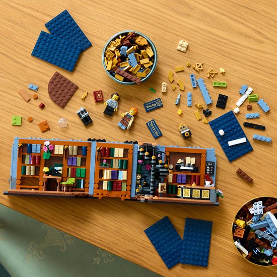 LEGO Boekhandel deels gebouwd, met losse stenen, minifiguren en bouwinstructies eromheen.