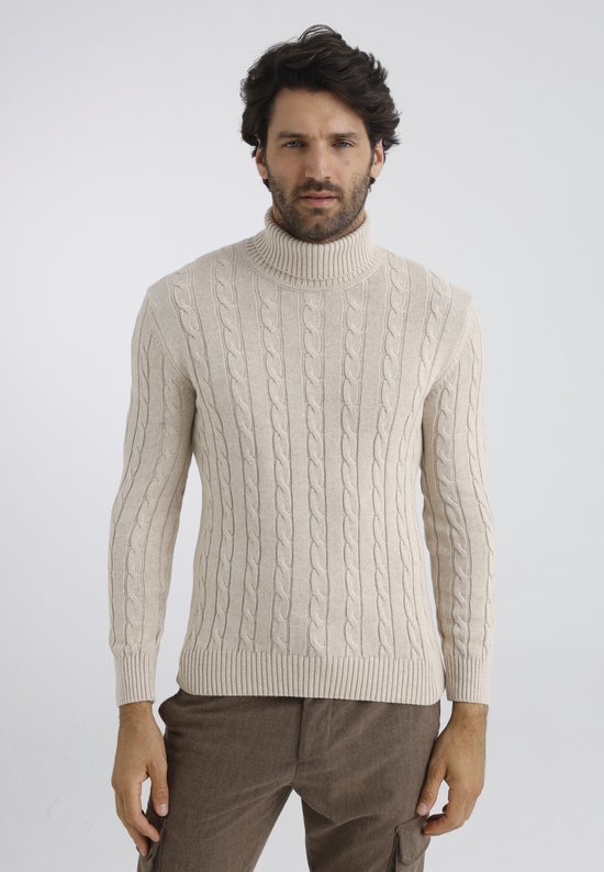 Man met beige coltrui met kabels en bruine broek.