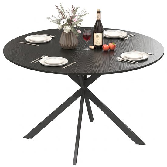 Ronde zwarte eettafel gedekt met servies, een bloemenvaas, wijn en appels.