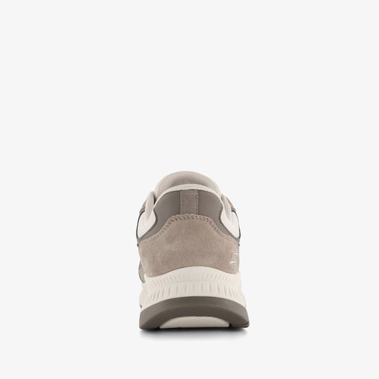 Achterkant van een beige sneaker met suède en mesh details, en een dikke witte en grijze zool.
