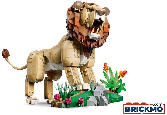 Gele lego leeuw met bruine manen, witte tanden en een groene, stenige omgeving met roze bloemen.