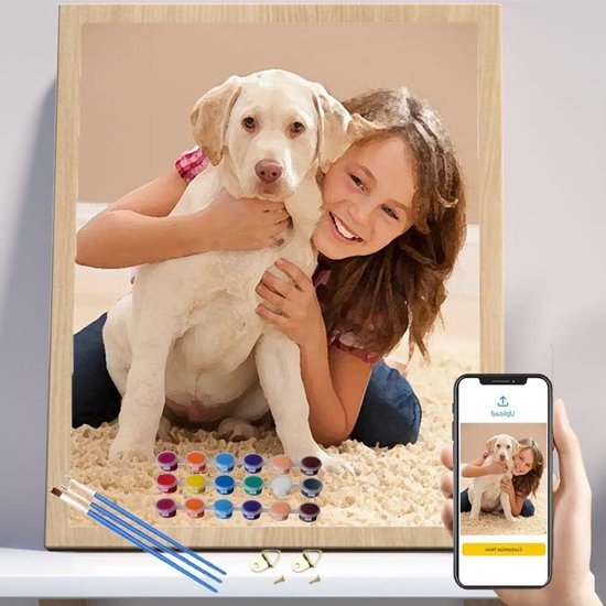 Une fille câline un chien, le tableau est affiché sur un téléphone avec un kit de peinture.