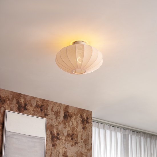 Beige, ovale lampenkap met geribd patroon, verlicht en gemonteerd aan het plafond.