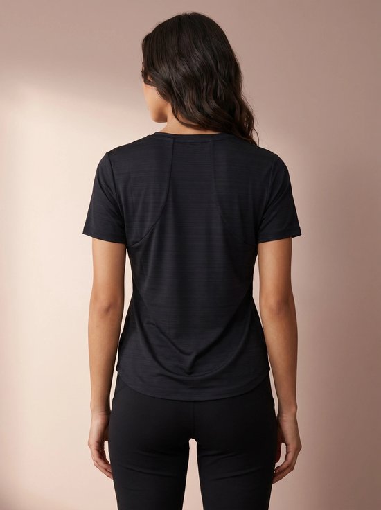 Vrouw in donkerblauw sportshirt met korte mouwen, van achteren gezien.