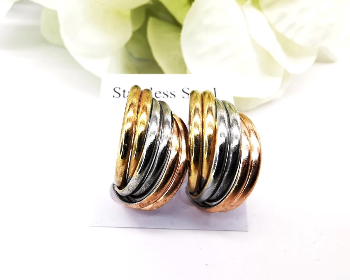 Oorbellen - roestvrij staal (stainless steel) - tricolor half-hoop oorbellen met een geribbeld en gelaagd ontwerp. De oorbellen combineren drie verschillende metaalkleuren: geelgoud, zilver/witgoud en roségoud/koper.