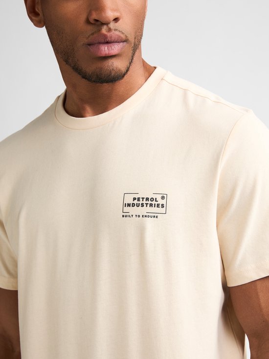 Close-up van een crème T-shirt met logo 'Petrol Industries Built to Endure'.