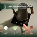 Zwarte waterkoker met houten handvat op een basis met display. Hand kiest 90°C voor instant koffie.