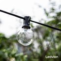 Eén G40 LED-lamp aan een zwart lichtsnoer tegen een groene, wazige achtergrond.