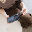 Een vrouw met rode nagellak plaatst een grijze AYO bril in de bijbehorende draagcase.
