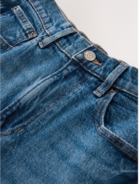 Detail van de tailleband en zakken van een blauwe spijkerbroek