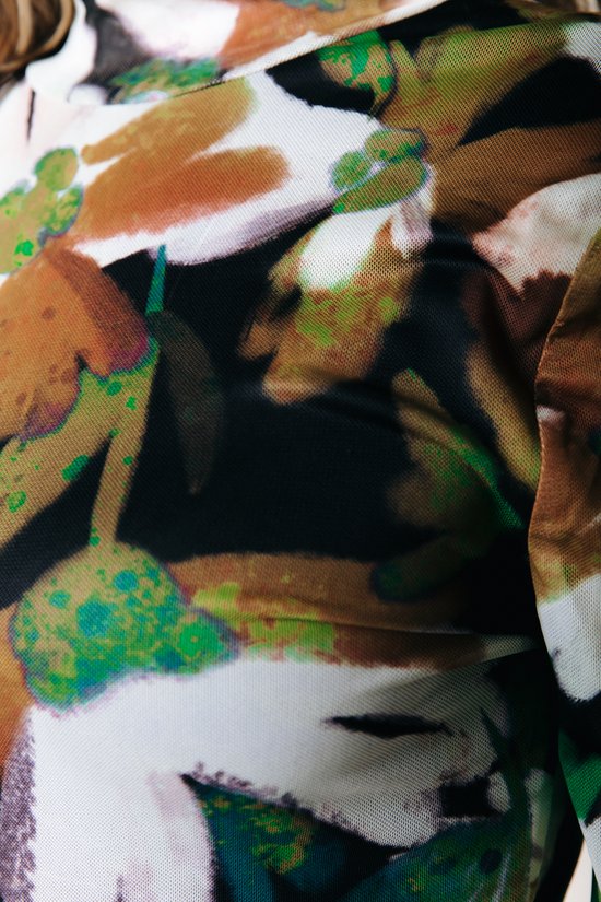 Close-up van een mesh top met een abstracte bloemenprint in bruin, groen en wit.