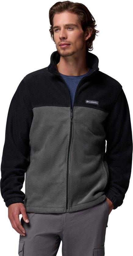 Un homme porte une veste polaire Columbia bicolore, noire et grise, à col haut et fermeture éclair intégrale.