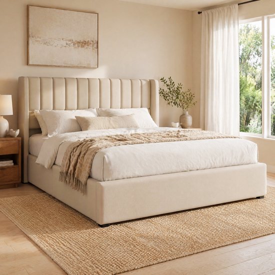 Beige gestoffeerd tweepersoonsbed met een gestreepte hoofdsteun, opgemaakte bedden, een plaid en een jute vloerkleed. Een nachtkastje met lamp staat aan de linkerkant.