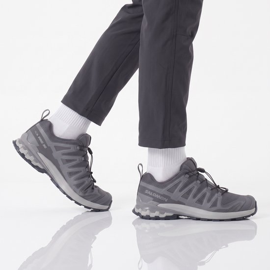 Model draagt grijze Salomon wandelschoenen met witte sokken.