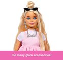 Close-up van Barbie met blonde abloom en zonnebril. Ze draagt een roze jurk en Barbie ketting. "So many glam accessories!"