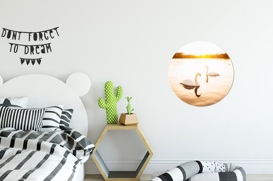Deux cygnes nagent dans l'eau pendant un coucher de soleil lumineux Assiette en plastique cercle mural Ø 30 cm - impression photo sur cercle mural / cercle vivant (décoration murale)