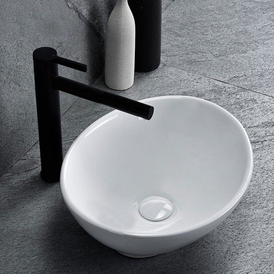 Lavabo blanc ovale à poser avec robinet noir, gros plan.