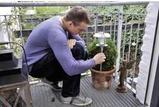 Man plaatst zonne-energie lampje met Varta batterij in pot met plant.