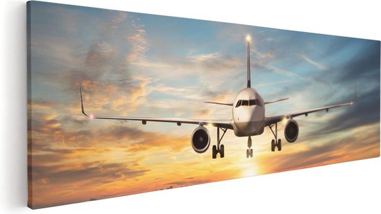 Toile d'un avion atterrissant sur la piste au coucher du soleil.