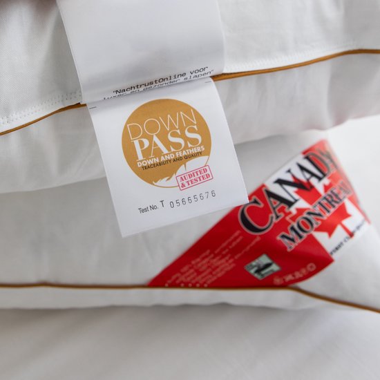 Detail van een witte kussen met bruine bies, met een "Down Pass" en "Canada Montreal" label.