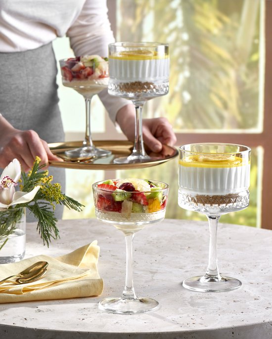 Glaasjes gevuld met fruitsalade en cheesecake.