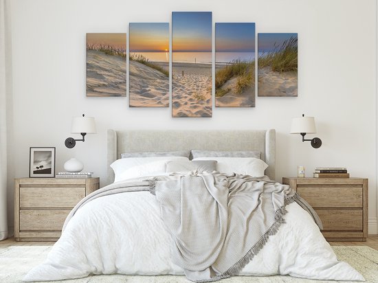 Vijfluik van een zandpad door de duinen naar de zee bij zonsondergang, met gras, zand en water.
