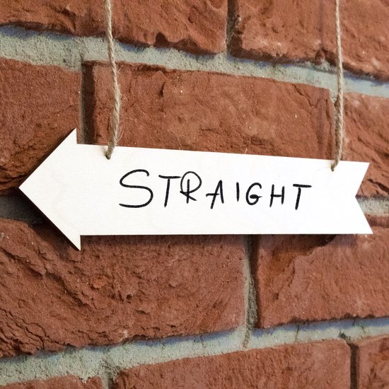 Houten pijl met de tekst 'STRAIGHT' hangt aan touw tegen een bakstenen muur.