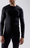 Man in zwart, nauwsluitend thermoshirt met lange mouwen, ribbelstructuur en grijze naden op schouders en armen.