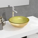 Lavabo ovale en verre doré avec un bord doré, posé sur un comptoir blanc.