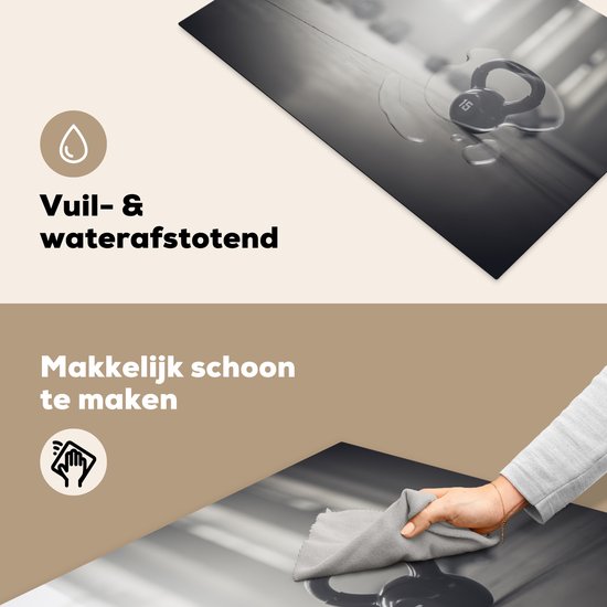 KitchenYeah® Inductie beschermer 76x51.5 cm - Verschillende kettlebellgewichten op de vloer in een fitnessruimte - Kookplaataccessoires - Afdekplaat voor kookplaat - Inductiebeschermer - Inductiemat - Inductieplaat mat