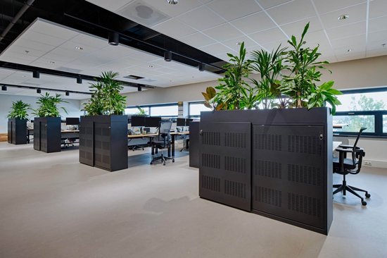 Donkergrijze scheidingswanden met plantenbakken in een kantoor met grijze vloer.