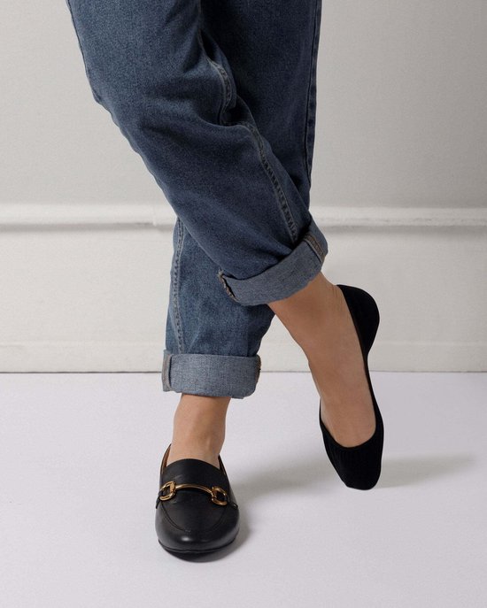 Zwarte instappers met goudkleurige gesp, gedragen met jeans.