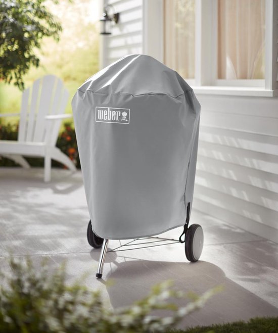 Grijze Weber barbecuehoes op een standaard met wielen, zichtbaar op een terras.