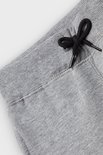 Detail van de tailleband en het trekkoord van een grijze joggingbroek.