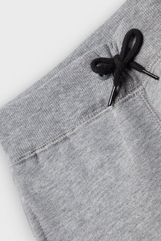 Detail van de tailleband en het trekkoord van een grijze joggingbroek.