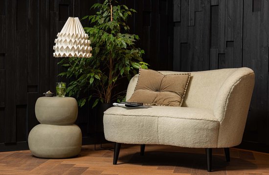 Grijze stapel bijzettafel van fiber clay, met een gebogen beige fauteuil en plant.
