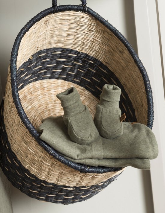 Des chaussons et une barboteuse kaki chiné dans un panier tressé à bord noir et marron.