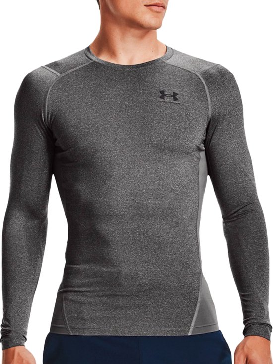 Man in grijze sport longsleeve met donkergrijze panelen aan de zijkanten en donkerblauwe short.