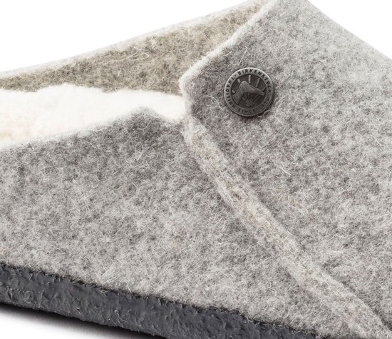 Grijze Birkenstock pantoffel van vilt met witte schapenwollen voering en een drukknoop.