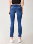 Achterkant van een model met een zwarte crop top, draagt een donkerblauwe, nauwsluitende jeans en witte sneakers.