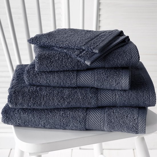 Pile de serviettes bleu foncé avec bord côtelé sur une chaise blanche.