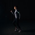 Vrouw met groene verlichte Bee-Safe armband tijdens het hardlopen in het donker.