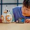 Un garçon regarde un BB-8 LEGO avec un côté qui s'ouvre et un présentoir.
