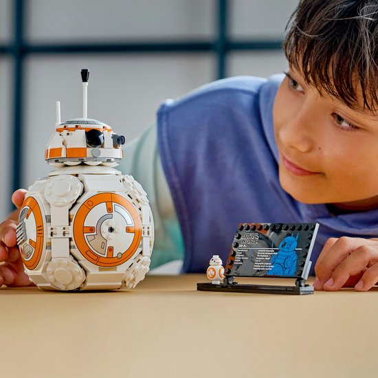 Un garçon regarde un BB-8 LEGO avec un côté qui s'ouvre et un présentoir.