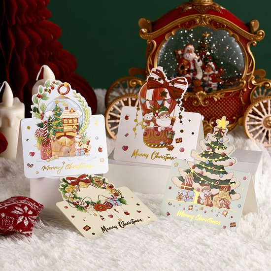 Vier kerstwenskaarten met opdruk van kerstbomen, kerstman, en cadeautjes. Goudkleurige 'Merry Christmas' tekst.